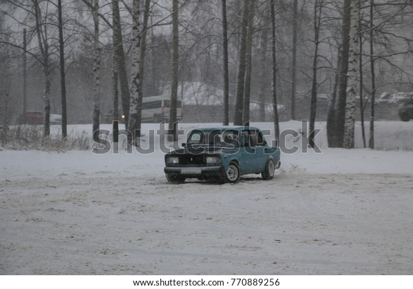 YOSHKAR-OLA, RUSSIA - DECEMBER 03,\
2017: Training in guided drifts on snow, ice and drifts into\
snowfall - drift on a rear drive car - on an empty car park in the\
city