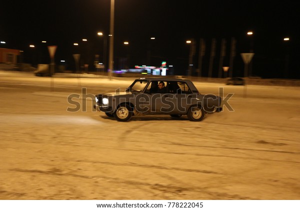 YOSHKAR-OLA, RUSSIA - DECEMBER\
12, 2017: Training in guided drifts on snow, ice and snowdrifts\
into snowfall,  drift on the rear-drive car-on an empty car park in\
the city