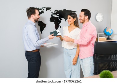 You Are All Set For Your Vacations. Sales Representative Giving Passports And Plane Tickets To A Young Woman And Man For Their Holiday Trip At The Travel Agency