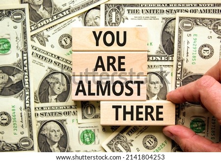You are almost there symbol. Concept words You are almost there on wooden blocks. Businessman hand. Beautiful background from dollar bills. Business and you are almost there concept. Copy space.