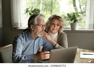 You always have my support, dear. Happy elderly married couple feel pleasantly surprised look on laptop screen read amazing news online. Smiling retired wife teach aged husband to use internet on pc - Powered by Shutterstock