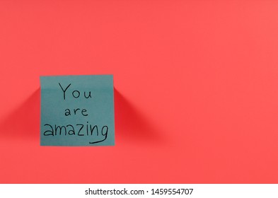You Are Amazing. Blue Sticky Note With Inspirational Quote On Neon Pink Background. Handwritten Positive Reminder/advice. Concept For Confidence, Courage And Motivation. Sign Of Moral Support.