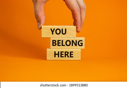 You belong here symbol. Wooden blocks with words 'You belong here' on beautiful orange background. Male hand. Diversity, business, inclusion and belonging concept. - Shutterstock ID 1899513880