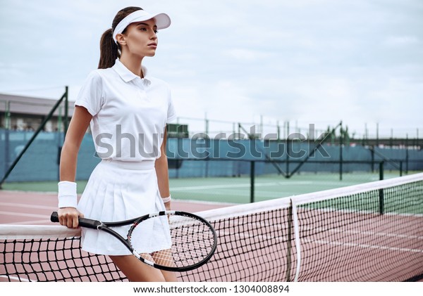 If you can\
believe it, the mind can achieve it. Beautiful tennis player in\
white sportswear looking\
away