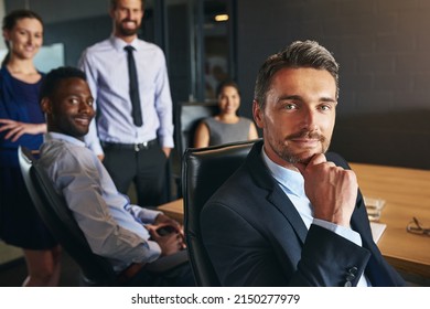 You Can Count On My Team. Portrait Of A Businessman Sitting In An Office With Colleagues In The Background.