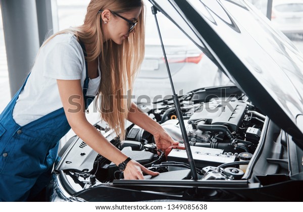 You can see all the\
details. On the lovely job. Car addicted woman repairs black\
automobile indoors.