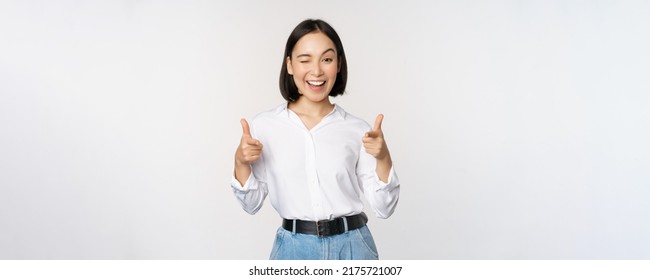 Its you congrats. Smiling attractive asian woman, businesswoman pointing fingers at camera with pleased face, complimenting, inviting you, standing over white background - Powered by Shutterstock