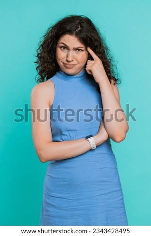 You are crazy, out of mind. Displeased woman pointing at camera, show stupid gesture finger near head, blaming some idiot for dumb insane plan idea, senseless talk. Girl on blue background. Vertical