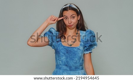 You are crazy, out of mind. Lovely pretty young woman pointing at camera and showing stupid gesture, blaming some idiot for insane plan. Adult stylish girl isolated on gray studio background indoors