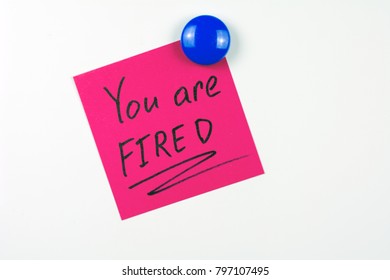 You Are Fired Note Reminder Red Sticker On The White  Fridge Door Attached Blue Round Magnet, Close Up