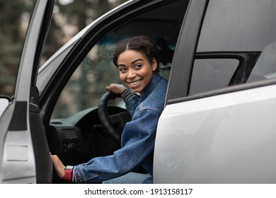 Are you going with me. Friendly smiling millennial african american female driver opens door and looks for fellow traveler, sitting in silver car or lady gets out of auto and looks back, copy space - Shutterstock ID 1913158117