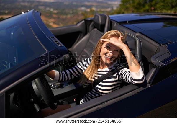 You like fast cars. Shot of a young woman driving in\
a sports car.