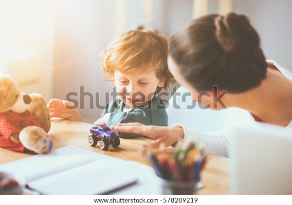 You\
make me happy. Delighted young thoughtful mother playing with her\
little child using toys and sitting at the\
table.