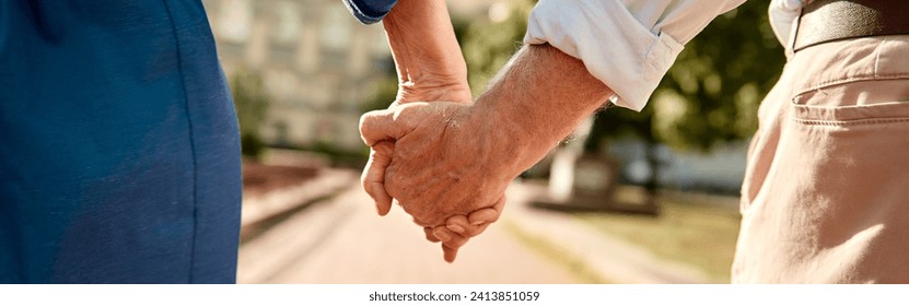 You and me forever. Close-up of elderly couple holding hands while walking together outdoors - Powered by Shutterstock