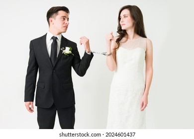 You Are Mine Forever. Gorgeous Bride Looking At Her Upset Sad Groom While Handcuffed Together On Their Wedding Day