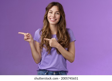 You need see yourself introduce new product. Enthusiastic happy smiling toothy girl curly hairstyle promoting cool cafe menu pointing index finger left smiling broadly stand purple background - Shutterstock ID 2005745651