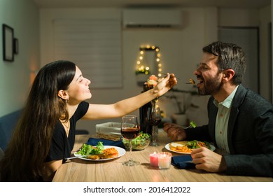 You Need To Try This. Romantic Young Woman Giving Food To Her Partner While Enjoying A Fancy Dinner Together At Home