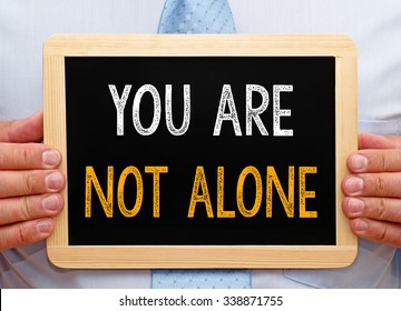 You are not alone - Businessman holding chalkboard with text
