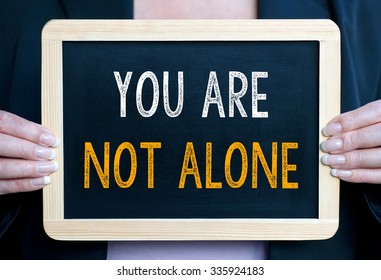 You are not alone - Businesswoman holding chalkboard with text