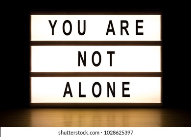 You are not alone light box sign board on wooden table. 