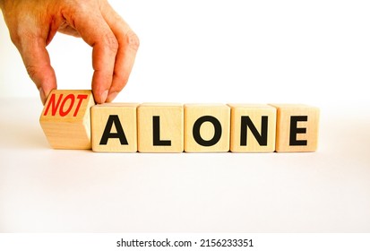 You are not alone symbol. Businessman turns wooden cubes and changes concept words alone to not alone. Beautiful white background. Business, support and you are not alone concept. Copy space. - Shutterstock ID 2156233351