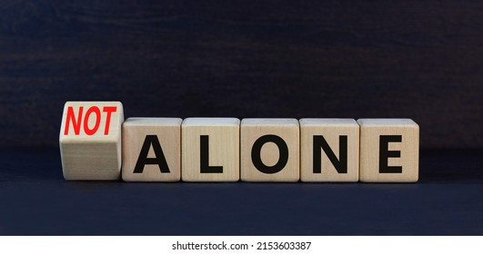 You are not alone symbol. Turned wooden cubes and changed concept words alone to not alone. Beautiful black table black background. Business, support and you are not alone concept. Copy space. - Shutterstock ID 2153603387