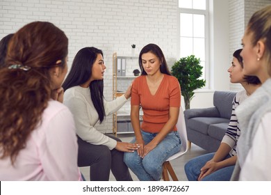 You are not alone. Women helping sad young woman who's been victim of emotional abuse and domestic violence, comforting her and showing their solidarity in support group meeting or therapy session