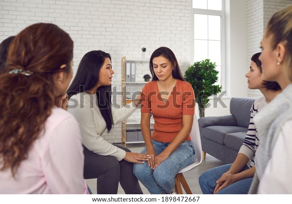 You are not alone. Women helping sad young woman\
who\'s been victim of emotional abuse and domestic violence,\
comforting her and showing their solidarity in support group\
meeting or therapy session