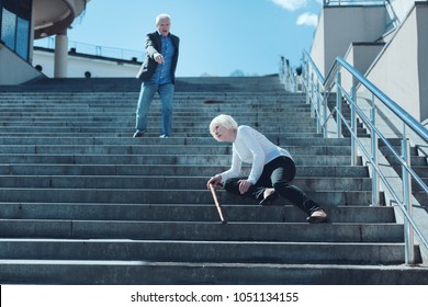 Are you ok. Mindful senior husband shouting to his wife while seeing her falling down on stairs and feeling pain in her leg.