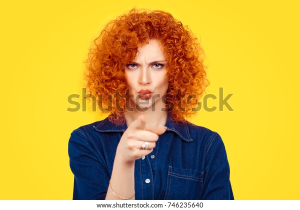 It\'s you! Portrait angry annoyed redhead curly\
hair woman getting mad pointing finger at you camera showing hand\
gesture this is you, you chosen, isolated on yellow wall\
background.  Negative\
emotions