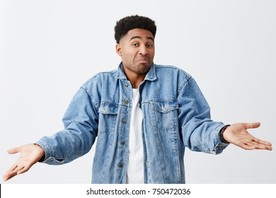 As you say, bro. No problem. Isolated on white portrait of funny dark-skinned man in white t-shirt and denim jacket spreading hands with unsure face expression. - Shutterstock ID 750472036