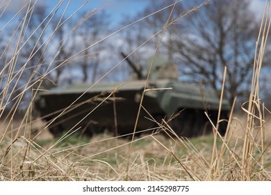 You See Blades Of Grass In Focus And Behind Out Of The Focus Is A Russian Military Tank