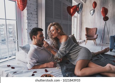 You should try it.  Beautiful young couple eating chocolate candies and drinking champagne while lying on the bed at home - Shutterstock ID 1021843933