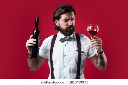 You Should Try This. Brutal Guy Bartender In Bow Tie. Elegant Male Barman. Handsome Hipster Drinking Wine Glass. Sommelier Tasting Alcohol. Bearded Man In Suspenders Drink Red Wine.