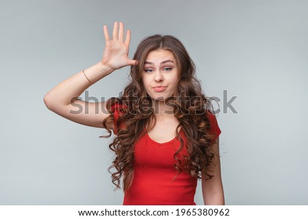 Are you stupid, out your mind. Young brunette woman asking, gesturing are you crazy, out of your mind, twisting for finger at his temple. Body language, signs and gestures. Gray background