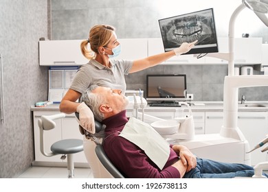 Are you sure you understand it. Side view of the attractive grey haired senior man looking concerned at the x ray while listening to what his doctor explaining to him. Dentistry concept - Powered by Shutterstock