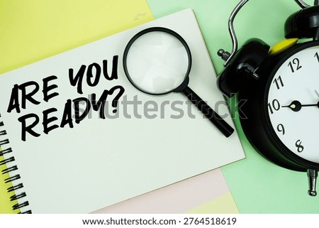 Are You Ready? text written on notepad with alarm clock on pastel background