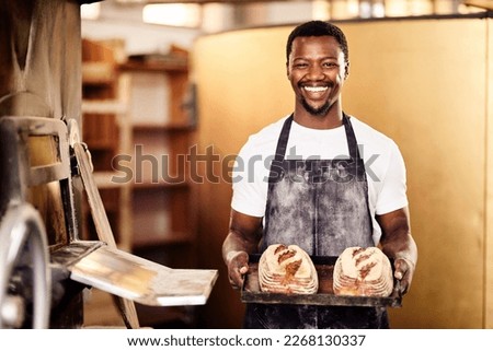 If you want fresh then come to my bakery. Cropped shot of a male baker holding up freshly baked bread in his bakery.
