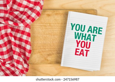 You Are What You Eat Message In Recipe Notebook On Kitchen Table, Concept Of Guidelines For Proper Nutrition With Copy Space, Top View.