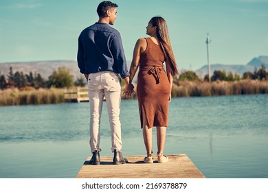 You are the whole of my heart. Rearview shot of a young couple holding hands while standing together on a pier at a lakeside. - Powered by Shutterstock