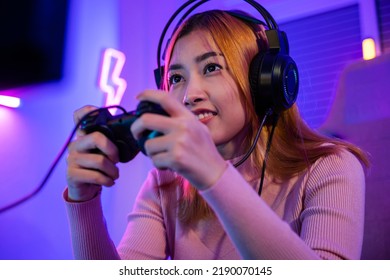 You win. Gamer using joystick controller plays online video game with computer neon lights she winning, woman wear gaming headphones playing live stream esports games console at home celebrating win