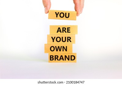 You are your own brand symbol. Wooden blocks with words You are your own brand. Beautiful white background, copy space. Businessman hand. Business, you are your own brand concept.