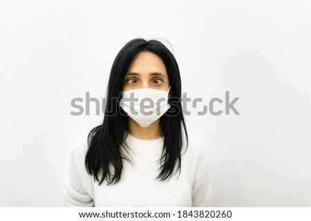 Youn caucasian woman shows crazy eye look down to whte face mask. concept of sickness and human sillyness.