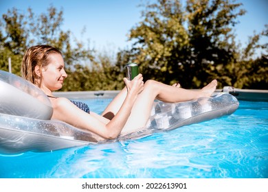 Youn Woman Holding Beer Can Floating On The Blue Pool Water And Relaxing In The Swimming Pool. Copy Space