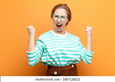 yound blonde woman feeling happy, surprised and proud, shouting and celebrating success with a big smile