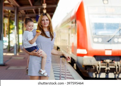 Yound Woman And Little Girl, Lovely Daughter, On A Railway Station. Kid And Woman Waiting For Train And Happy About A Journey. People, Travel, Family, Lifestyle Concept