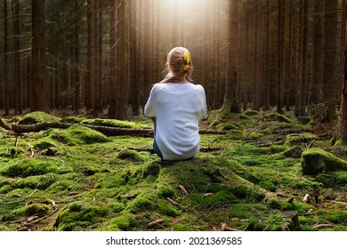 Younf female sitting alone in green forest enjoys the silence and beauty of nature.