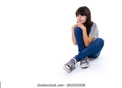 junges 10-jähriges Mädchen sitzt auf Bodenruhe mit Händen auf dem Knie und lächelt in die Kamera mit Kopienraum einzeln auf Weiß