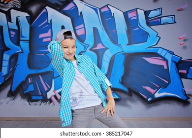 young 10-years boy posing in front of a colorful graffiti wall. Teenager boy dancing hip hop over textured background