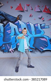 young 10-years boy posing in front of a colorful graffiti wall. Teenager boy dancing hip hop over textured background